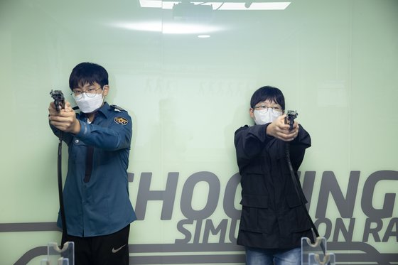 문제원(왼쪽)·안강 학생기자가 사격 체험실에서 3.8 구경 권총으로 시뮬레이션 사격에 열중하고 있다.