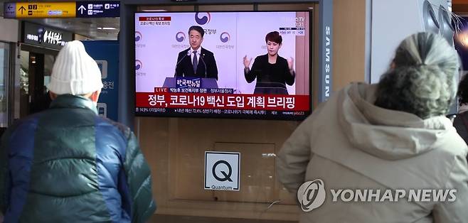 코로나19 백신 확보 브리핑 보는 시민들 (서울=연합뉴스) 임헌정 기자 = 8일 서울 중구 서울역에서 시민들이 정부의 코로나19 백신 확보 브리핑을 TV화면으로 지켜보고 있다. 2020.12.8 kane@yna.co.kr