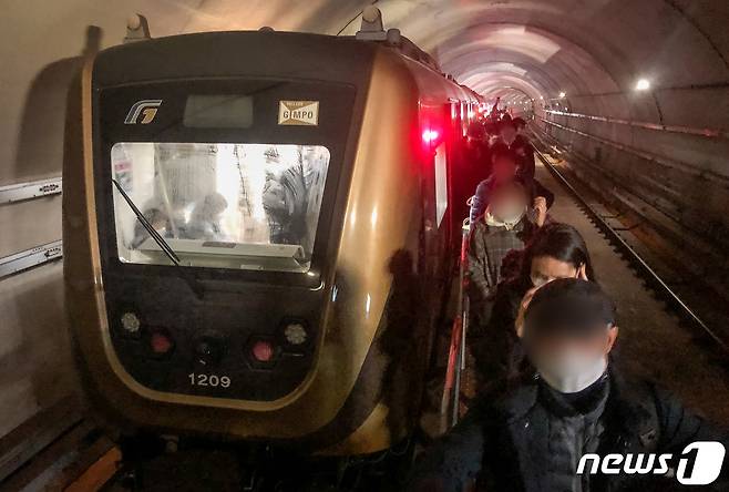21일 오후 6시 30분께 김포 골드라인 경전철이 김포공항역에서 고촌역사이에서 멈춰서 시민들이 큰 불편을 겪고 있다. 이 차량에 50여분간 갇혀 있던 약 300여명의 승객들이 열차 선로 위 비상통로로 고촌역까지 걸어가고 있다. 2020.12.21/뉴스1 © News1 김명섭 기자