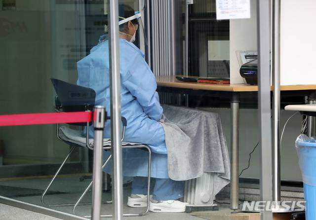 [서울=뉴시스]최진석 기자 = 22일 서울 국립중앙의료원 선별진료소에서 한 관계자가 전기 라디에이터와 무릎 담요로 추위를 피하고 있다. 2020.12.22. myjs@newsis.com