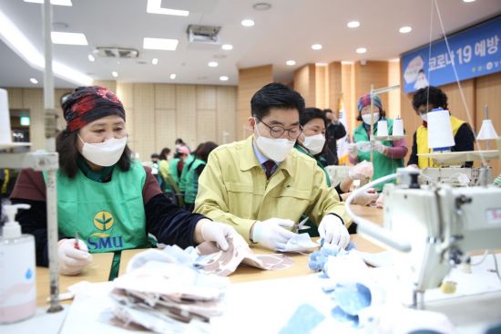 지난 3월 강동구청 5층 대강당에서 이정훈 강동구청장이 새마을부녀회 회원들과 함께 코로나19 예방 천 마스크를 만들고 있다.