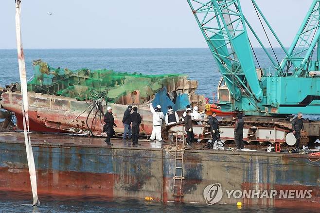 모습 드러낸 32명민호 선체 (제주=연합뉴스) 박지호 기자 =  제주 해경과 인양업체 관계자들이 4일 오후 제주항 서방파제 앞 해상에서 지난달 29일 전복돼 침몰한 32명민호 선체 부분을 인양하고 있다. 2021.1.4 jihopark@yna.co.kr