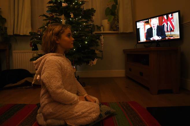 보리스 존슨 영국총리가 TV를 통홰 3차 봉쇄조치를 발표하는 장면을 한 소녀가 집에서 바라보고 있다./연합뉴스