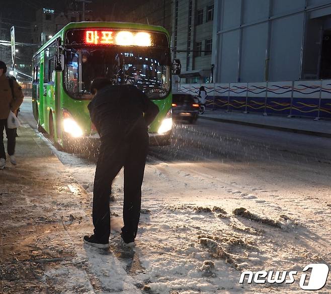 6일 오후 곳곳에 한파와 대설 특보가 발효된 가운데 서울 마포구 홍대입구역 인근에 눈이 소복히 쌓여있다. 한 시민이 인도의 눈을 쓸고 있다.2020.1.6/뉴스1 © News1 황덕현 기자