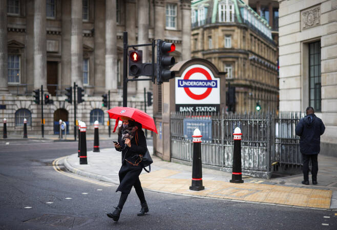 5일(현지시간) 한 시민이 빨간 우산을 들고 한산한 런던 거리를 지나고 있다. 런던은 이날부터 필수목적 외에 통행을 제한하는 3차 봉쇄에 돌입했다. 런던|로이터연합뉴스