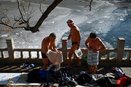 6일 중국 베이징에서 3명의 남성이 얼음 목욕을 마친 뒤 옷을 챙겨입고 있다./사진=AFP