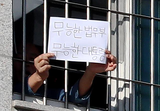 6일 오후 서울 송파구 서울동부구치소에서 한 수용자가 '무능한 법무부 무능한 대통령'이라고 쓴 종이를 창문 밖으로 내보이고 있다. 연합뉴스