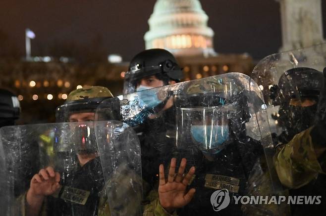 미 의사당 앞 거리에서 시위 진압 나선 주 방위군 (워싱턴 AFP=연합뉴스) 미국 주 방위군이 6일(현지시간) 워싱턴DC 연방의회 의사당 앞 거리에서 시위대 해산에 나서고 있다. 도널드 트럼프 대통령 지지 시위대는 이날 의사당에 난입했다가 4시간 만에 쫓겨난 뒤에도 의사당 주변에서 시위를 이어갔다. sungok@yna.co.kr