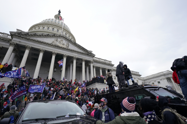 트럼프 미 대통령 지지 시위대가 지난 6일 워싱턴DC 연방의사당 경비 경찰차의 지붕 위에 올라 서 있다./AP 연합뉴스