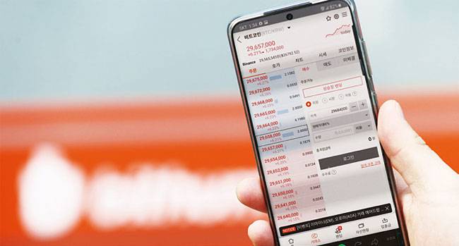 지난해 12월 27일 빗썸 서울 강남센터 앞에서 한 시민이 비트코인 시세를 보고 있다. 사진 연합뉴스