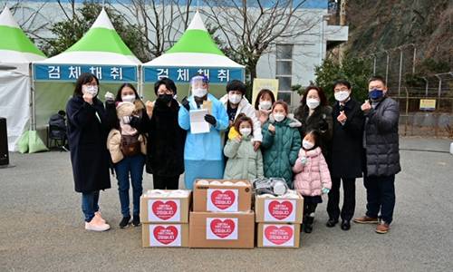부산 사하구 임시 선별검사소 인근 주민들이 의료진을 위해 핫팩, 손난로 등 성품과 손편지를 전달하고 기념촬영을 하고 있다. 뉴스1