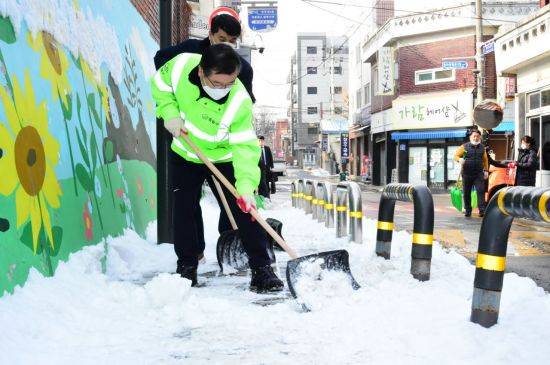 류경기 중랑구청장이 주민들과 함께 망우3동 면일초등학교 통학로 주변 제설작업을 하고 있다.