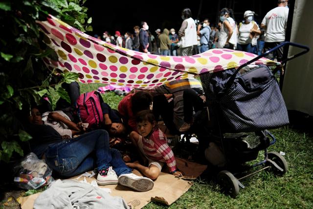 온두라스 산페드로술라의 버스 정류장 앞에서 14일 온두라스인들이 중남미 이민자 행렬의 출발을 기다리며 휴식을 취하고 있다. 산페드로술라=로이터 연합뉴스