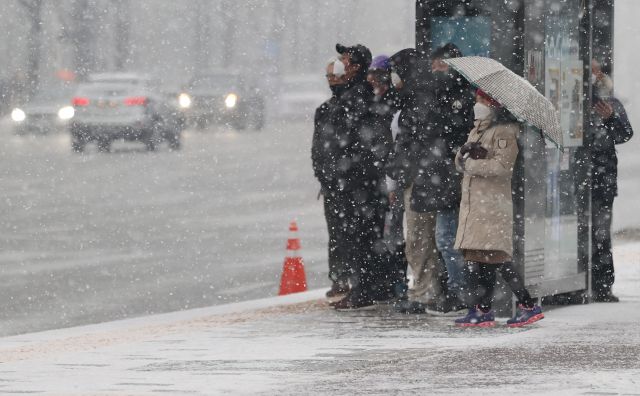 서울에 눈이 내린 지난 12일 오후 서울 광화문 사거리 인근 버스정류장에서 시민들이 버스를 기다리고 있다. 연합뉴스