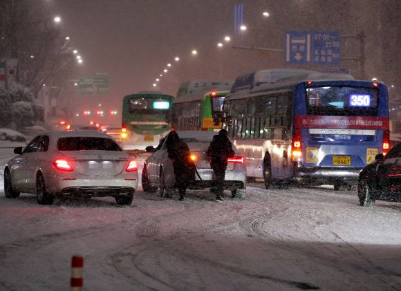 서울 전역에 대설주의보가 발효된 6일 오후 서울 삼성역 인근 도로에서 시민들이 차를 밀고 있다. 2021.1.6 연합뉴스