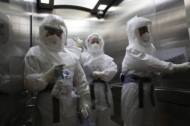 Nurses dressed in protective gear take the elevator up to the COVID-19 ward at the SMC.