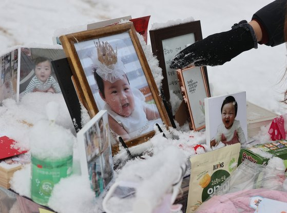 13일 경기도 양평군 하이패밀리 안데르센 공원묘원에서 한 시민이 양부모의 학대로 생후 16개월 만에 숨진 정인 양을 추모하며 쌓인 눈을 치우고 있다.연합뉴스