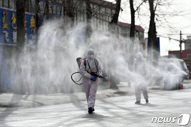 지난 15일 중국 허베이성 스자좡 코로나19 위험 지역으로 선포된 지역 한 거리에서 방호복을 입고 소독약을 분무 중인 중국 당국 관계자들. © AFP=뉴스1
