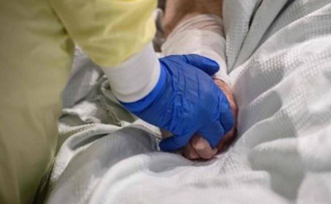 미 매사추세츠주 우스터의 UMASS 메모리얼 DCU센터 야전병원에서 의료진이 코로나19 환자의 손을 잡아주고 있다. 연합뉴스