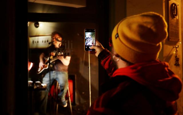 체코 프라하에서 21일 한 시민이 문 닫은 바 안에서 공연 중인 가수의 모습을 휴대폰으로 촬영하고 있다. 프라하=로이터 연합뉴스