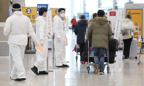 19일 오후 인천국제공항 제1터미널 입국장에서 해외입국자들이 방역관계자로부터 안내를 받고 있다. 연합뉴스