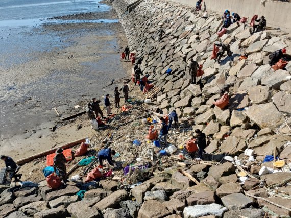 공무원과 어민들이 해안가의 방치된 쓰레기를 수거하고 있다.