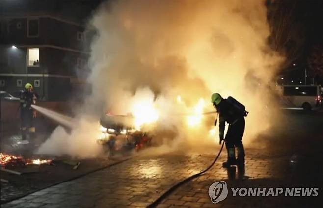 25일(현지시간) 네덜란드 하를럼에서 폭도들이 자동차에 불을 지른 것을 소방관이 끄고 있는 장면을 담은 영상 이미지. [Mizzle Media via AP=연합뉴스. 재판매 및 DB 금지]