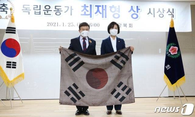 25일 서울 여의도 광복회관에서 열린 ‘’독립운동가 최재형상‘’ 시상식에서 ‘’최재형상‘’을 받은 추미애 법무부 장관이 김원웅 광복회장과 임시의정원 걸개 태극기를 들고 기념 촬영을 하고 있다. (광복회 제공) 2021.1.25/뉴스1 (서울=뉴스1)