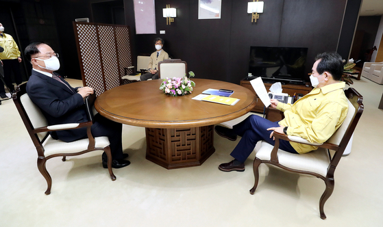 On Tuesday, Prime Minister Chung Sye-kyun, right, takes a look at a document before instructing Hong Nam-ki, Vice Prime Minister for Economic Affairs and Finance Minister, to find ways to effectively subsidize losses for the self-employed and small merchants as a result of government enforced social distancing measures to control the coronavirus. [YONHAP]