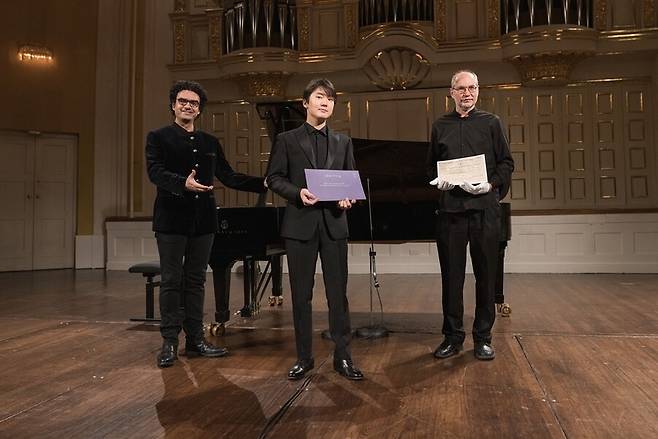 피아니스트 조성진이 모차르트 미공개 곡 ‘알레그로 D장조’를 세계에서 처음으로 연주했다. 이 곡은 지난 27일(현지시각) 오스트리아 잘츠부르크에서 열린 ‘모차르트 주간’(27~31일)에 온라인으로 공개됐다. 조성진(가운데)이 ‘모차르트 주간’ 예술감독이자 테너 롤란도 비야손(왼쪽)과 울리히 라이징거 모차르트협회 연구소장(오른쪽)과 함께 ‘알레그로 D장조’ 악보 등을 들고 선 모습. 유니버설뮤직 제공