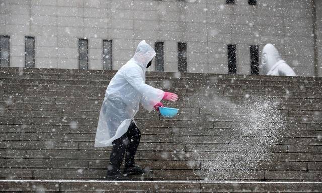 서울 지역에 대설주의보가 발효된 28일 오전 서울에 눈이 내리자 종로구 세종문화회관 계단에 직원들이 염화칼슘을 뿌리고 있다. 뉴시스