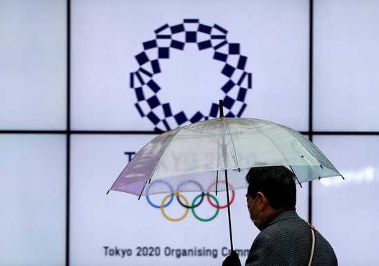 일본 도쿄에서 한 시민이 마스크를 쓰고 우산을 든 채 도쿄올림픽 홍보물 앞을 지나고 있다. /사진=로이터