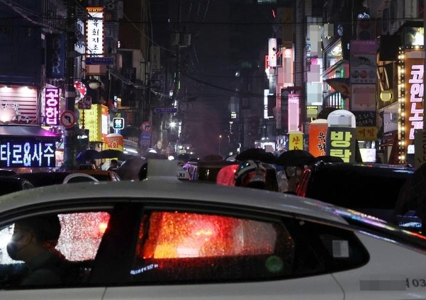 21일 밤 유흥시설들이 들어선 서울 송파구 잠실새내역 인근 거리에 밤 9시가 넘어 간판 불을 밝힌 업소들 사이로 시민들이 귀가하고 있다.