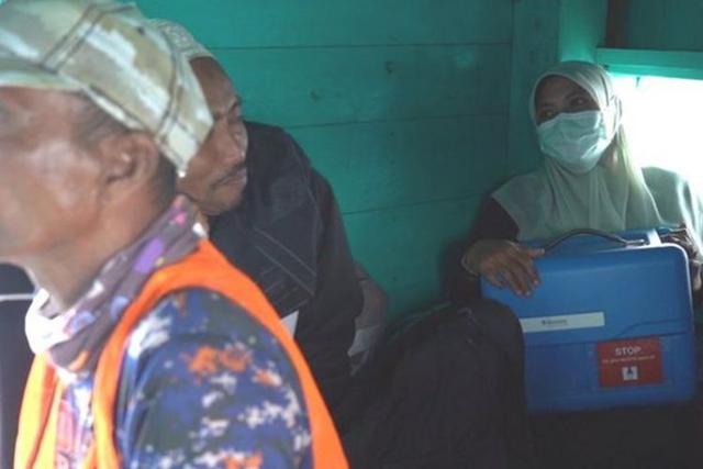 보건소 직원 아리나씨가 코로나19 백신이 들어있는 파란 상자를 자신이 일하는 섬으로 운반하기 위해 여객선 조타실에 탔다. BBC인도네시아 캡처