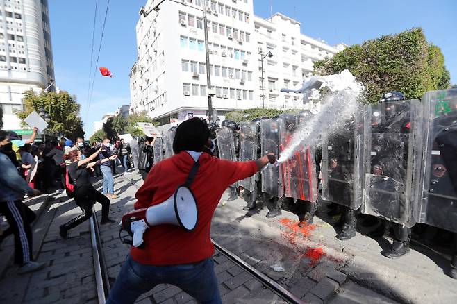“튀니지의 봄은 멀었다” 30일(현지시간) 튀니지에서 반정부 시위대가 경찰과 대치하던 중 물을 뿌리고 피켓을 던지며 저항하고 있다.  튀니스 | EAP연합뉴스