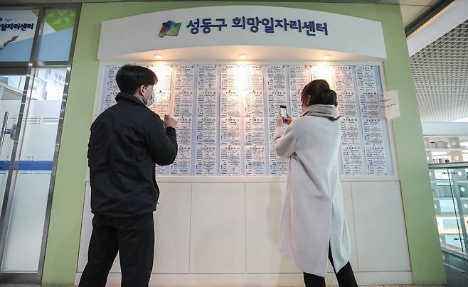 Civil servants at Seongdong-gu Office in Haengdang-dong, Seoul, look at a bulletin board for regional recruitment information. (Yonhap)