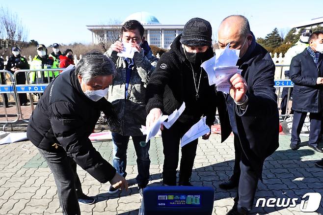 강제집합금지5개업종 비상대책위원회 회원들이 8일 오후 서울 영등포구 여의도 국회 앞에서 '형평성 없는 장기간 집합금지 업종 해제 및 손실보상 기자회견'을 하던 도중 영업 허가증을 찢고 있다. 2021.2.8/뉴스1 © News1 황기선 기자