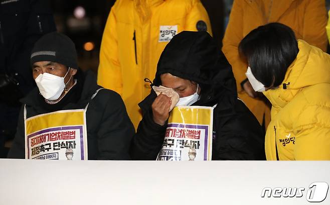 중대재해법 제정을 촉구하며 지난달 11일부터 단식에 들어갔던 고 김용균씨의 어머니 김미숙씨(왼쪽 두번재)가 지난 1월8일 저녁 중대재해처벌법 제정안이 국회 본회의를 통과 후 국회 본관 앞 농성장에서 열린해단식에서 눈물을 흘리는 모습2021.1.8/뉴스1 © News1 박세연 기자