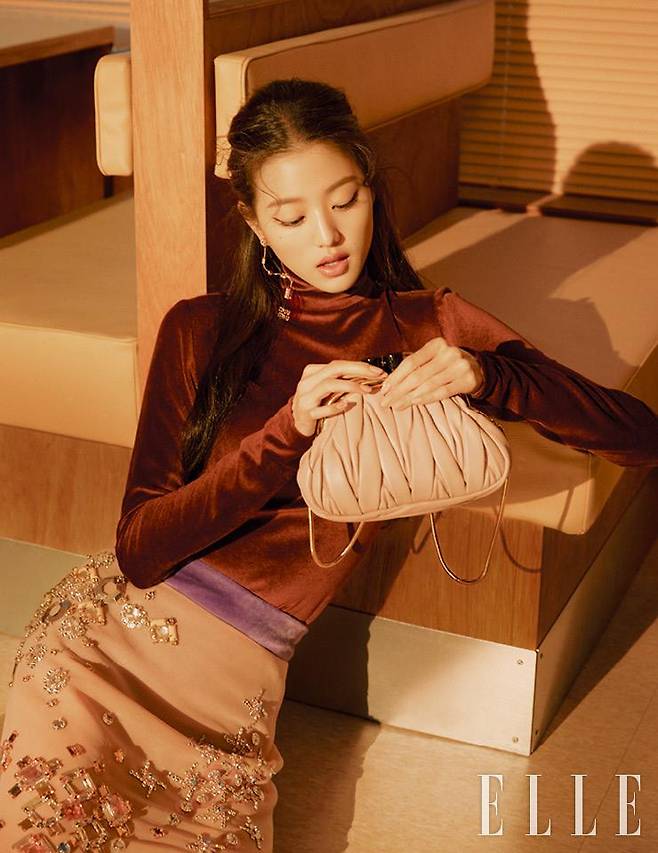 벨벳 소재의 브라운 터틀넥과 퍼플 이너 쇼츠, 주얼 장식의 핑크 스커트, 드롭 이어링, 미우 벨 백은 모두 Miu Miu.