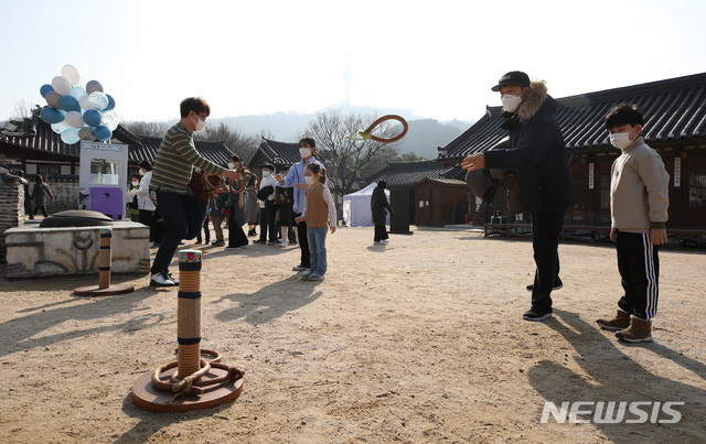 [서울=뉴시스]조수정 기자 = 민족 최대의 명절 설인 12일 오후 서울 중구 남산골 한옥마을에서 열린 '명랑소설' 행사에서 시민들이 쇠코뚜레 걸기 체험을 하고 있다. 2021.02.12. chocrystal@newsis.com