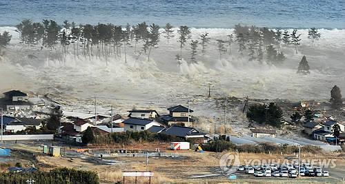 동일본대지진이 발생한 2011년 3월 11일 일본 미야기현의 해안가 마을에 거대한 쓰나미가 밀려들고 있다. [교도=연합뉴스 자료사진]