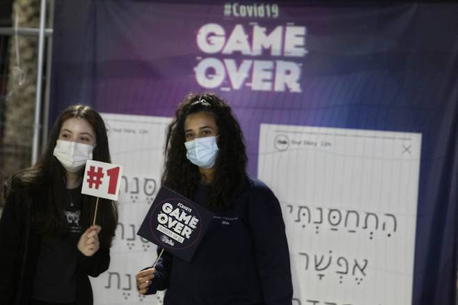 ‘코로나19 게임오버’ 이스라엘 홀론에서 한 청년이 코로나19 백신을 맞은 뒤 ‘GAME OVER’가 인쇄된 손팻말을 들고 사진을 촬영하고 있다.  홀론 | AP연합뉴스