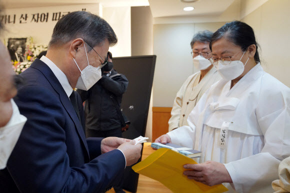 문재인 대통령이 17일 오전 서울 종로구 서울대병원 장례식장에 마련된 고 백기완 통일문제연구소장 빈소를 조문한 뒤 유가족으로부터 고인의 저서를 건네받고 있다. 뉴스1