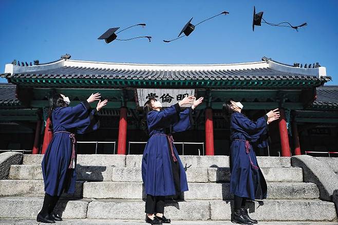 코로나 시름 잠시 잊고, 즐기자 기쁜 우리 졸업날 - 17일 서울 종로구 성균관대 명륜당 앞에서 전통 학위복을 입은 졸업생들이 학사모를 머리 위로 던지고 있다. 코로나 확산 방지를 위해 성균관대는 이날 졸업식을 유튜브로 중계했다. 학위 수여 자축 인증 사진 행사도 열었다. /뉴시스