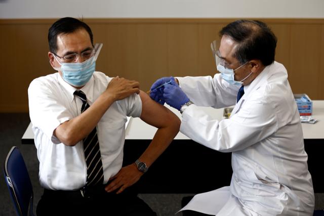 일본의 첫 코로나19 백신 접종자인 아라키 가즈히로(新木一弘) 도쿄의료센터 원장(왼쪽)이 17일 화이자 백신을 접종하고 있다. 도쿄=AP 뉴시스