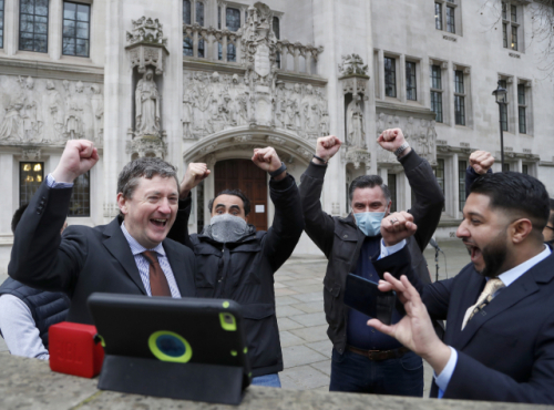 영국 앱 드라이버·배달원 노조 소속 우버 운전자둘이 19일(현지시간) 런던의 대법원 앞에서 스마트폰으로 판결 내용을 접한 뒤 환호하고 있다. /AP연합뉴스