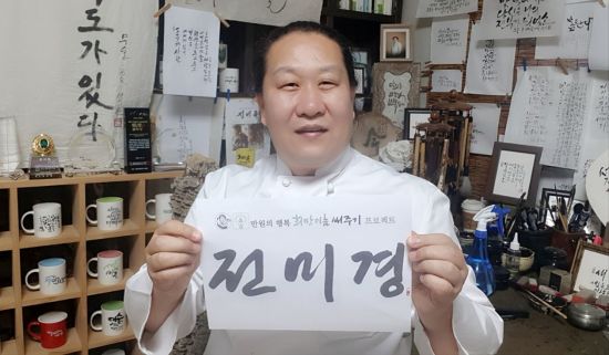 대한민국 캘리그래피 명장 석산 진성영 작가가 만원의 행복 희망이름 써주기 프로젝트에 참여한 김정옥씨 이름을 써서 들어보이고 있다.