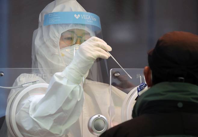A health care worker at a Seoul testing center performs a nasopharyngeal swab on a patient on Sunday. (Yonhap)