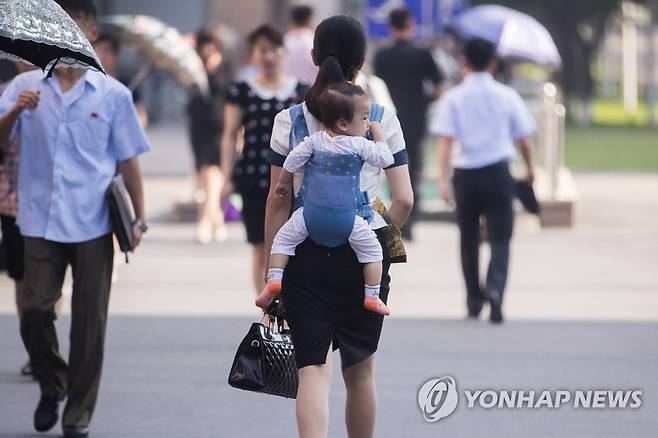 북한의 워킹맘 (평양=연합뉴스) 2018년 7월 4일 오전 평양 시내에서 한 여성이 정장 차림에 아이를 업고 길을 걷고 있다.[연합뉴스 자료사진·사진공동취재단] photo@yna.co.kr