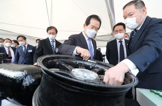 정세균 국무총리가 24일 오후 전주시 덕진구 한국탄소산업진흥원 개원식을 마친 뒤 효성 전주공장을 찾아 조현상 부회장(오른쪽)의 설명을 들으며 탄소섬유로 만들어진 자동차 휠을 들어보고 있다. [이미지출처=연합뉴스]